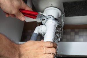 Close Up Of Male Plumber Fixing White Sink Pipe With Adjustable Wrench